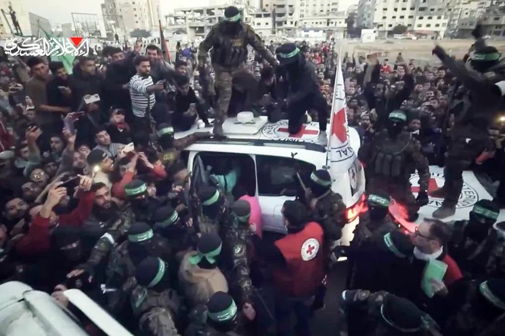 Militants and a crowd of people around an ambulance with two militants on its roof.